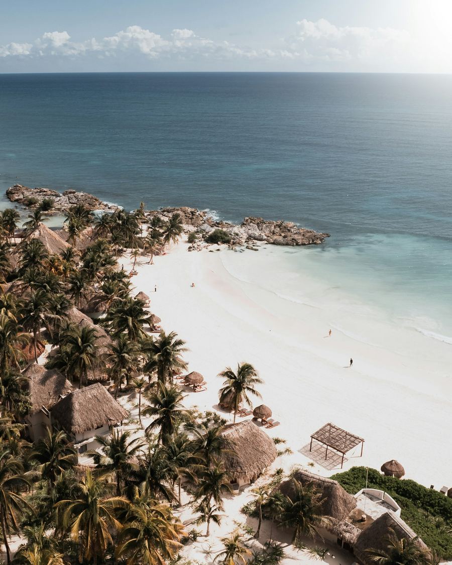 Aerial view of a white-sand Tulum beach with palms and the Caribbean Sea